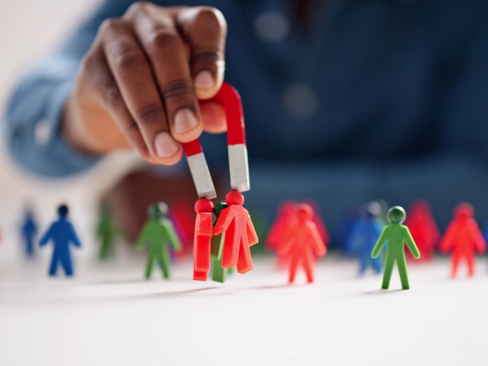 a person holding magnets to a group of miniature people