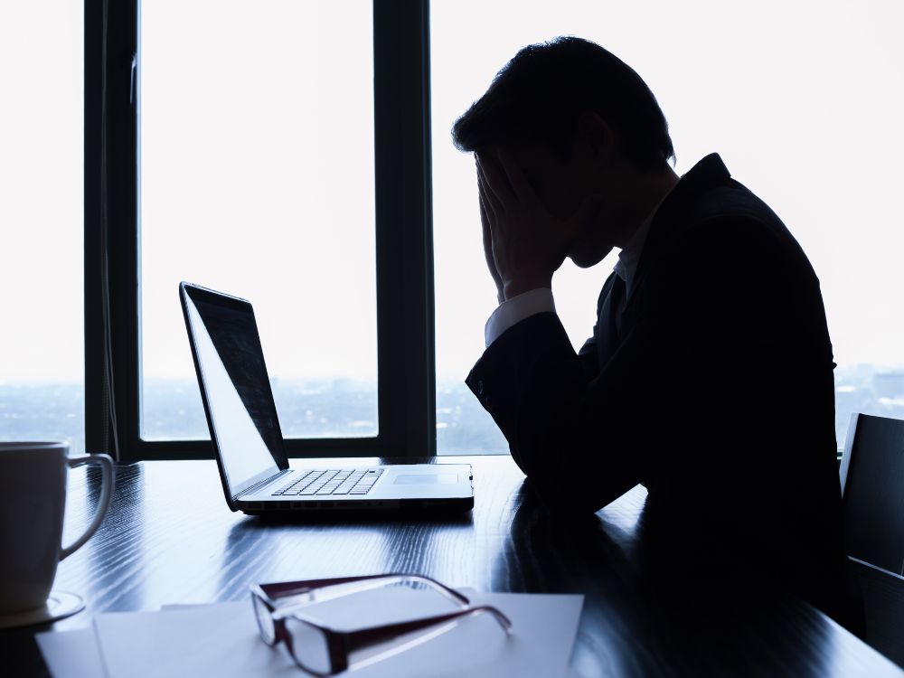 a man sitting at a desk with his hands in front of his face